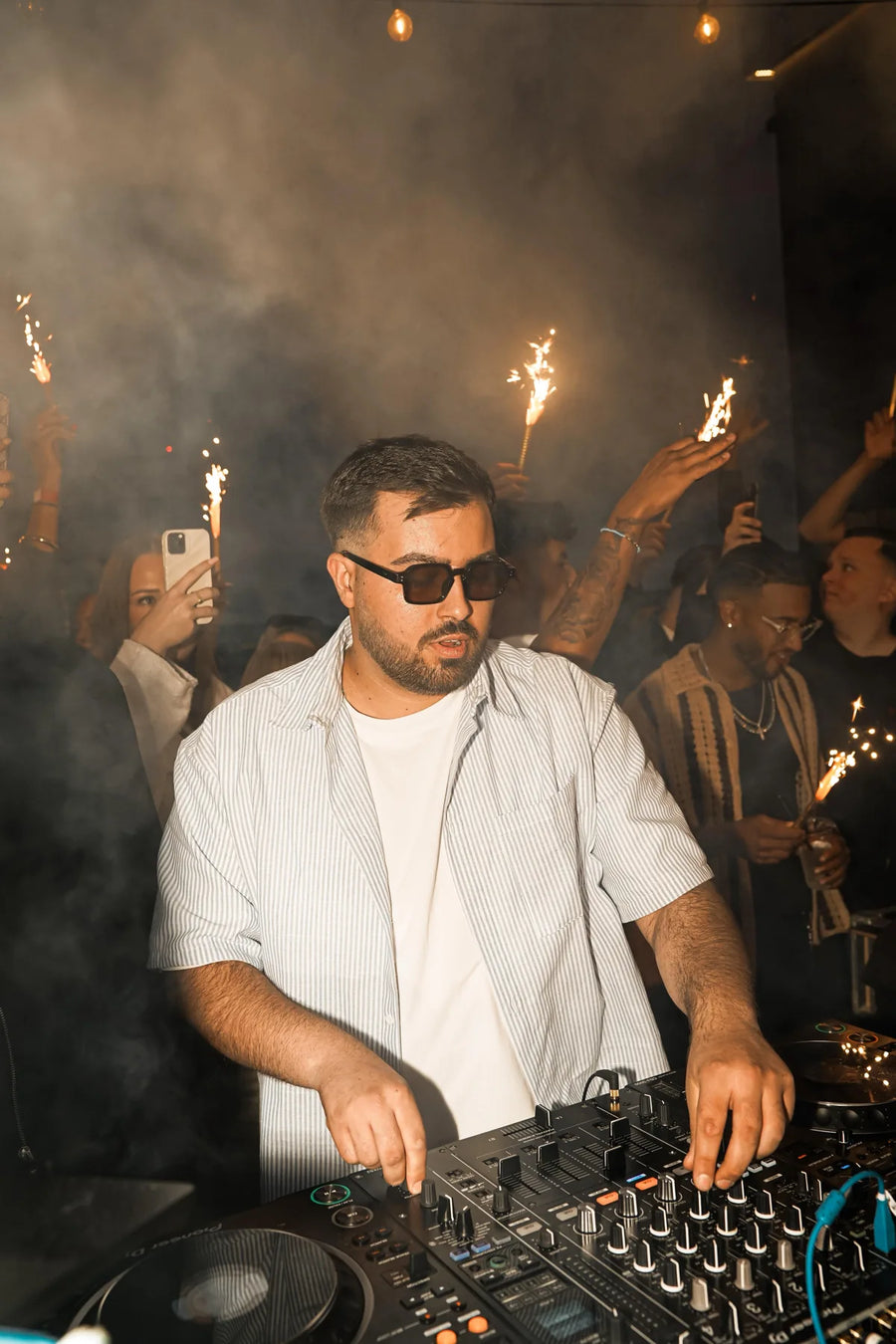 DJ am Mischpult mit Gästen und Wunderkerzen